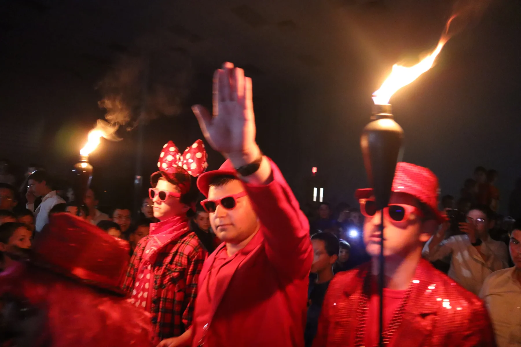 Camp performance featuring red costumes and flaming torches